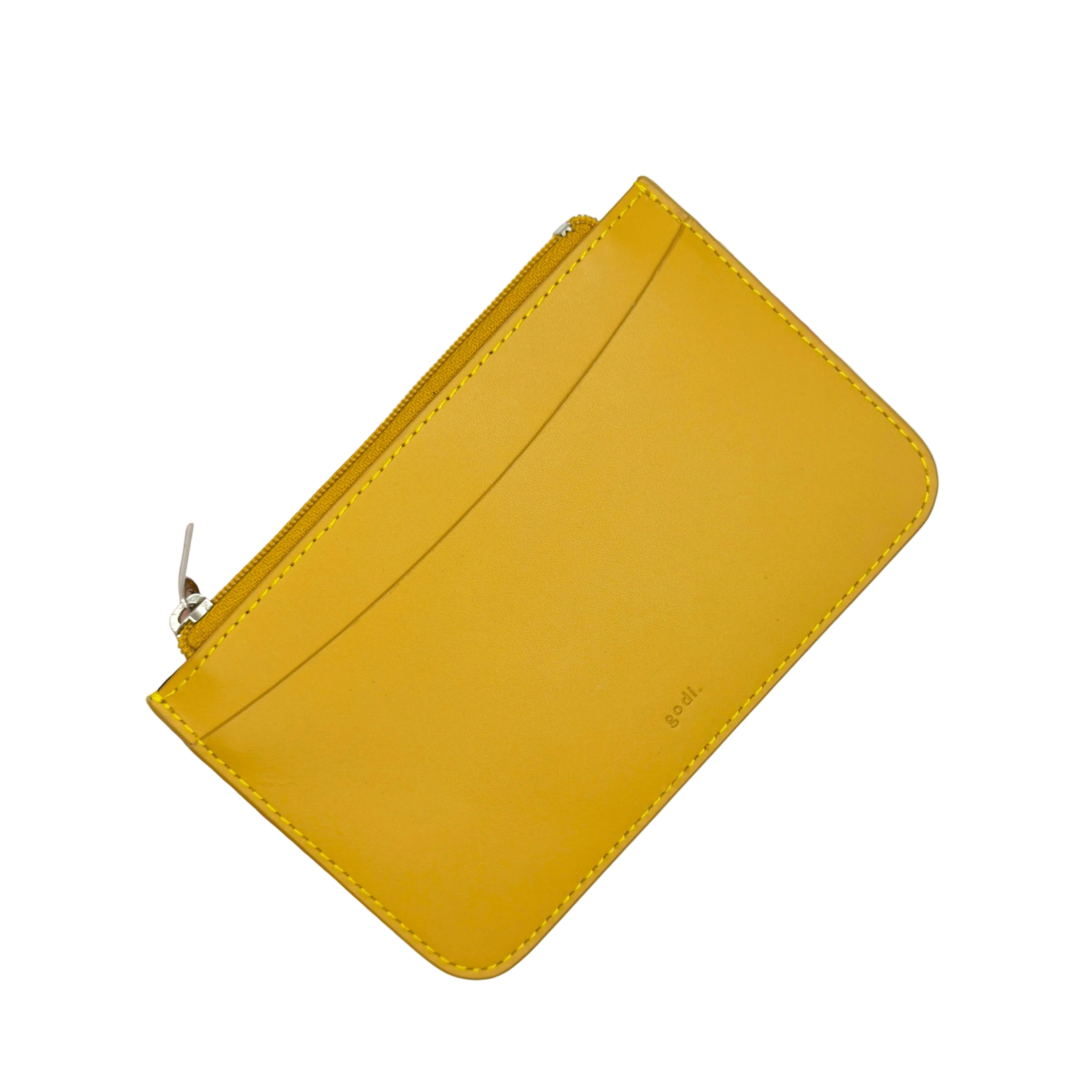 A hand holding a small yellow leather zip-around card holder or wallet with a visible silver zipper pull and subtle embossed branding on the front, set against a plain white background.