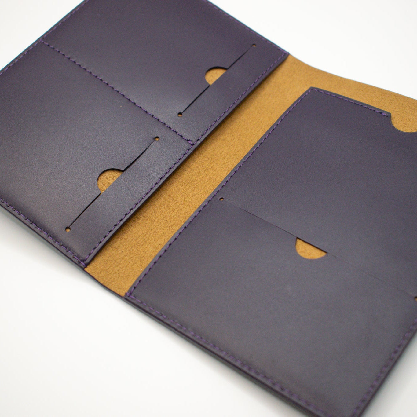Close-up of a purple leather wallet with brown interior on a white background
